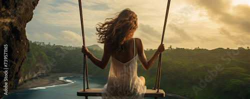 Woman swinging in sunset light. Rear view of girl swing against forest background. © Alena