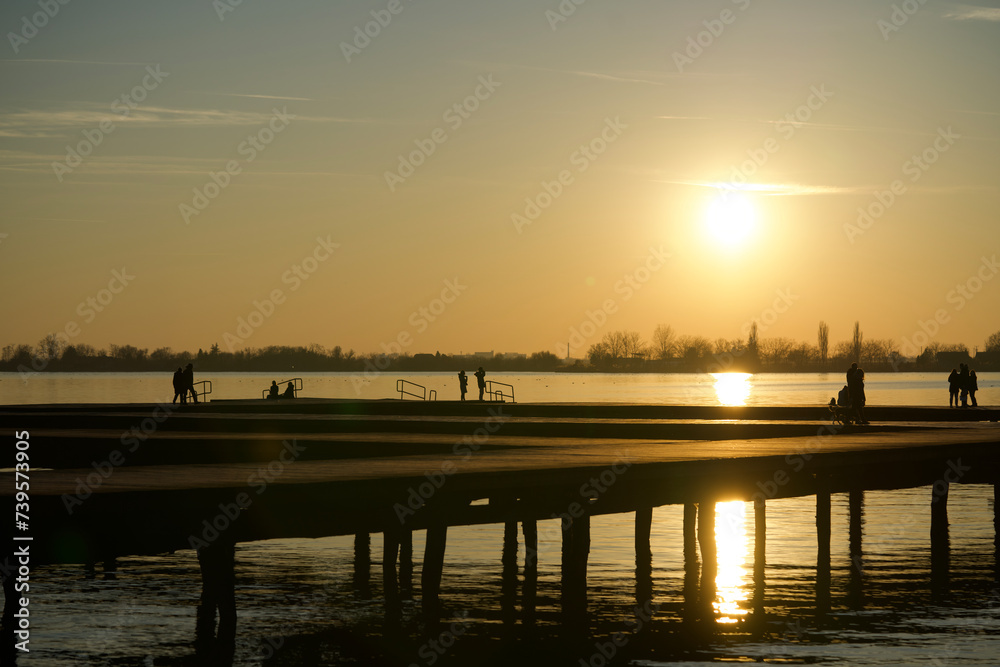 Dock on Lake Palic in Serbia near Subotica city with people enjoying a sunset walk and nice weather in February Dock on Lake Palic in Serbia near Subotica city with people enjoying a sunset walk and nice weather in February