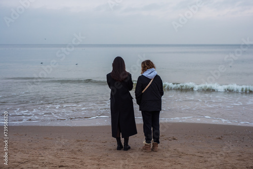 Two girls looking at the sea, back view