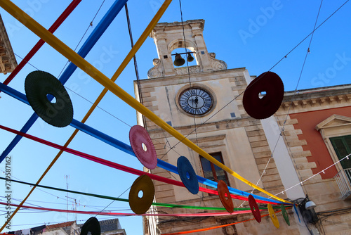 Fototapeta Naklejka Na Ścianę i Meble -  Clock tower in the historic center of Putignano, adorned with festoons for the carnival. Puglia, Italy