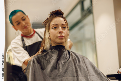 Female hairdresser is dying hair of client with brush while working in professional salon © Friends Stock