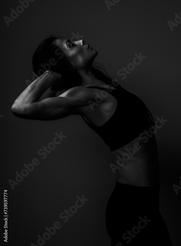 Athletic fitness woman in sport bra and black leggings doing gymnast backbend exercise behind on studio background with empty space. Closeup portrait. Black and white