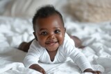 Smiling black baby girl in white bodysuit on cotton bed at home