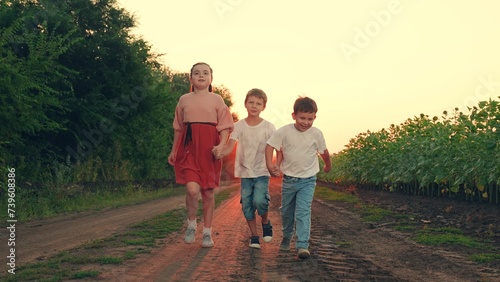 Happy boy, girl running, playing together in nature. Family, children travel in nature. Kids play, run through field of sunflowers, friends run at sunset. Happy Children dream concept. Brother sister
