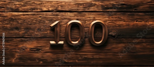 Large number 100 engraved on a rustic wooden surface for milestone anniversary celebration photo