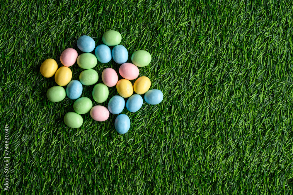 Naklejka premium Happy Easter, pastel colored candy coated Easter eggs on artificial green grass 