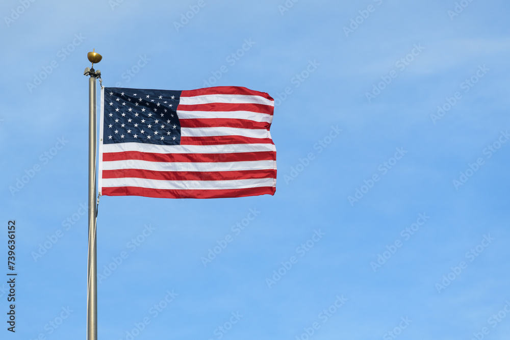 United States stars and stripes flag stretched in wind against blue sky
