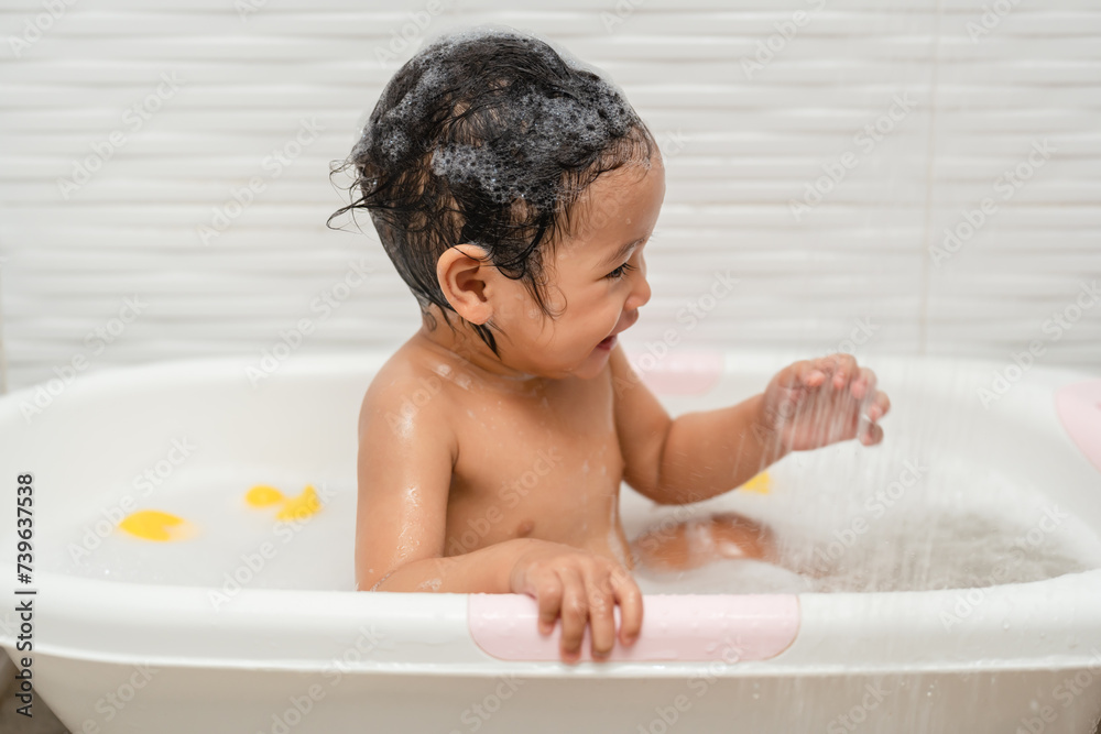 happy infant baby take a bath and playing under a shower in bathtub happy infant baby take a bath and playing under a shower in bathtub