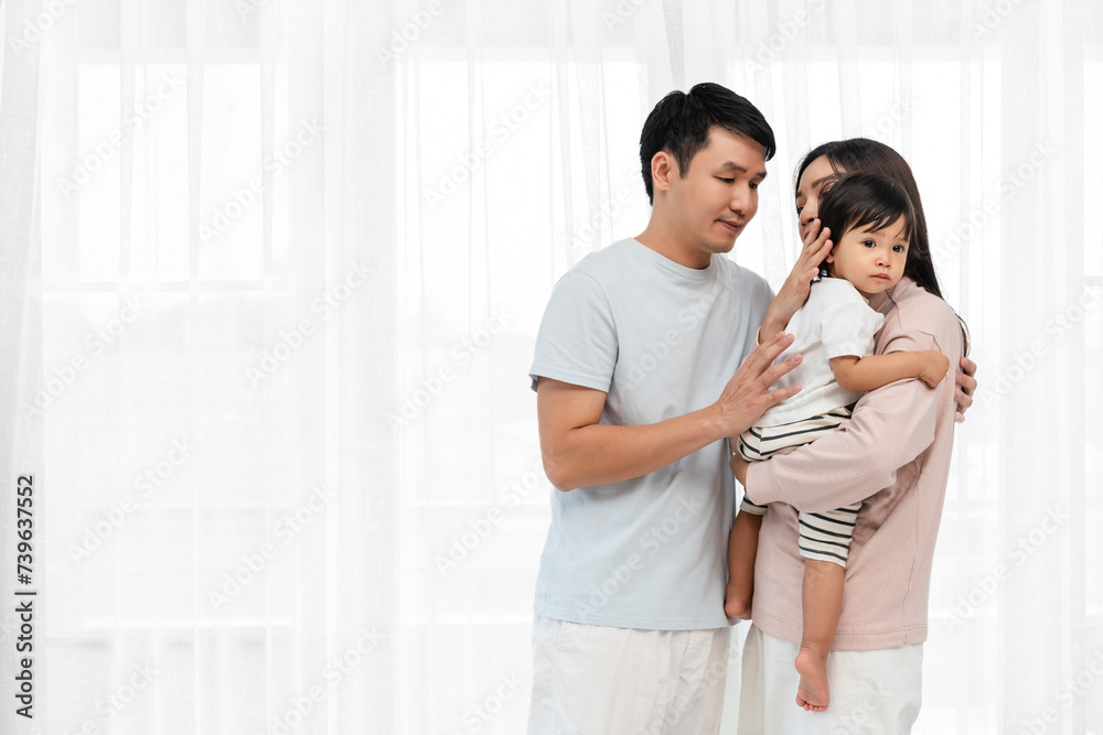 father and mother holding and hugging with toddler baby on white window background. happy family