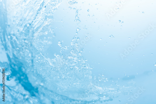 青の背景に波のように舞う水しぶき.