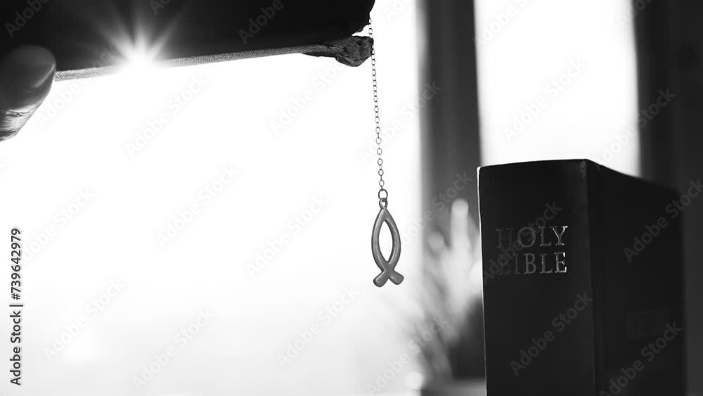 Christian reading the Bible while holding in his hand a fish-shaped ichthus symbolizing Christianity, worship and prayer background

