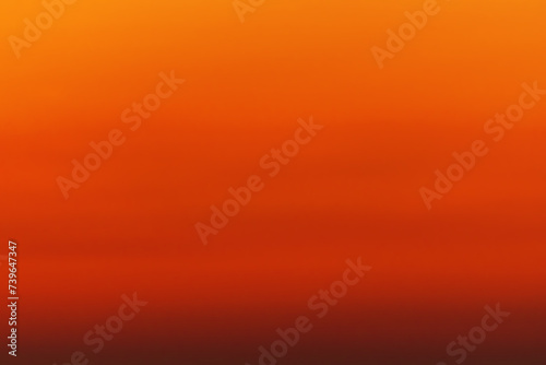 Orange red defocus shot of gradient sky at sunset over ocean horizon. The color changes from orange to dark red. Background, blank for artwork