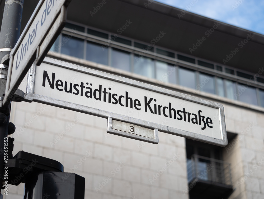 Fototapeta premium Neustädtische Kirchstrasse in Berlin. Sign with the road name at an intersection in the Mitte district. In this area are a lot of governmental buildings of the German administration.