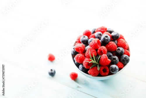 Ripe sweet blueberries and raspberries in a bowl. Closeup.