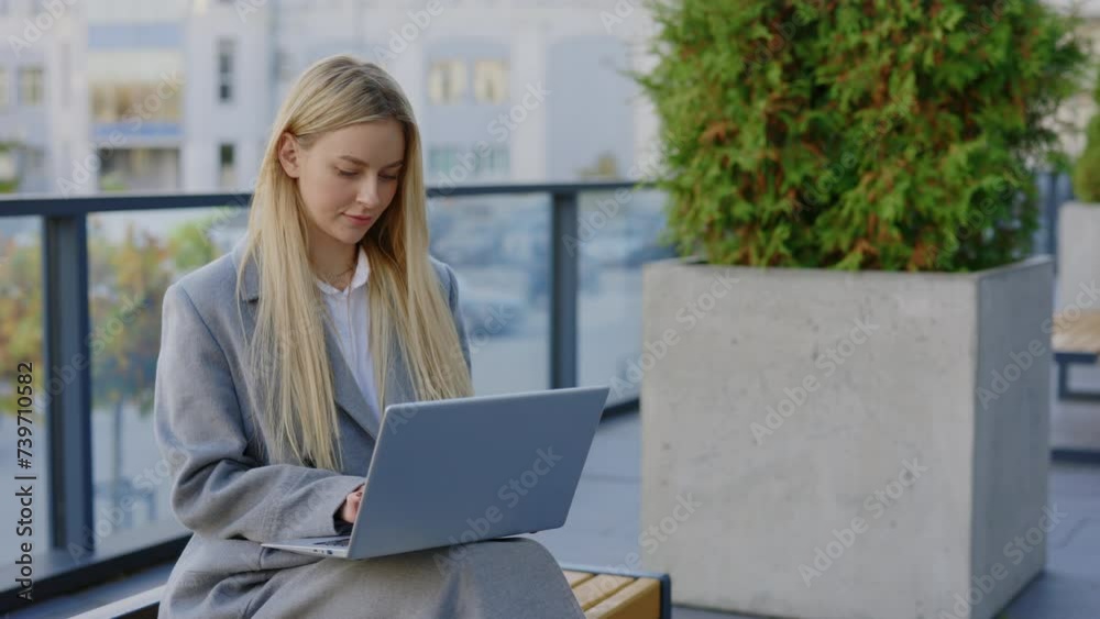 Beautiful Lady Seated on Bench Outside Modern Office Building, Engaged in Laptop Use. Woman Freelancer Working Online On Laptop. Technology and People Concept Beautiful Lady Seated on Bench Outside Modern Office Building, Engaged in Laptop Use. Woman Freelancer Working Online On Laptop. Technology and People Concept