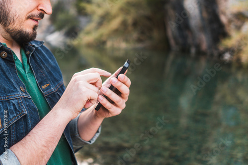 Man texting on phone by a river