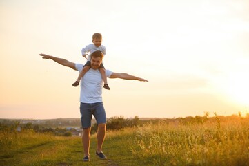 Happy father playing with son on sunset background .The concept of father's day