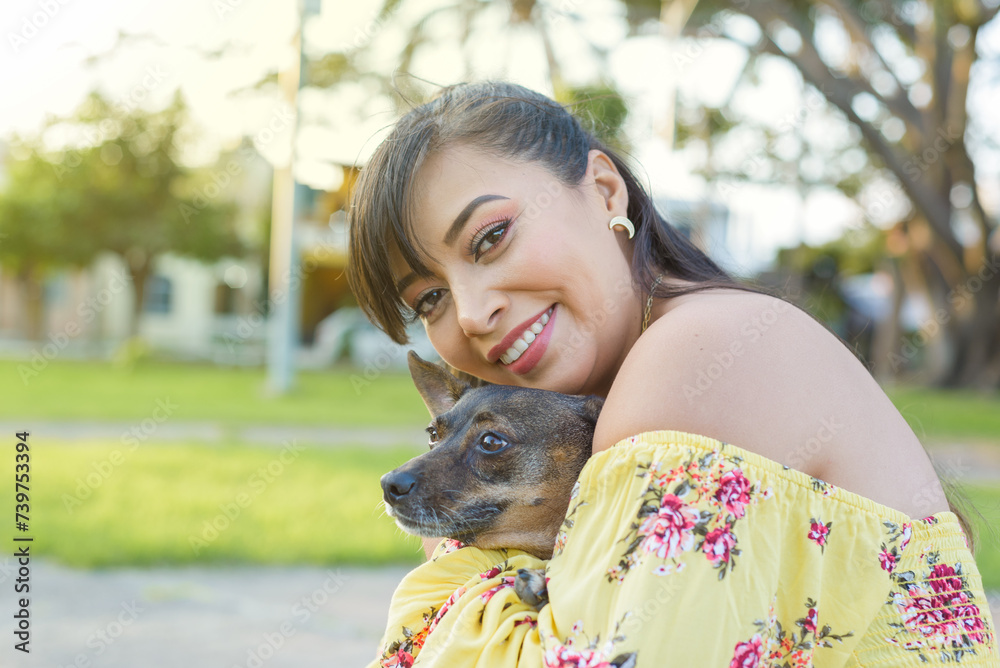 Obraz premium Woman hugging her pet in a public garden at sunset. Dog lover.