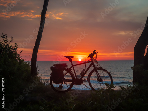 Peaceful scene with a bike silhouette against a colorful ocean sunset. Concept of leisure and travel. © Anton Gvozdikov