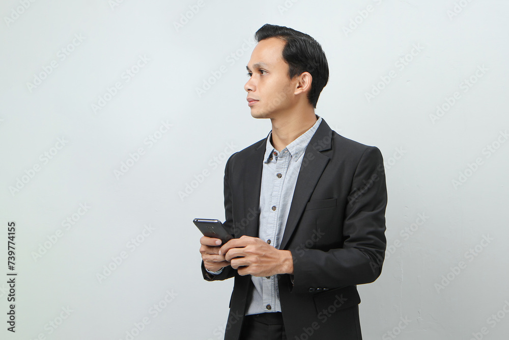 portrait of asian indonesian business man in suit holding smart phone on isolated background portrait of asian indonesian business man in suit holding smart phone on isolated background