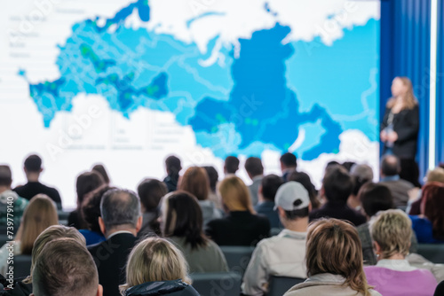 Focused shot of a business presentation to a diverse audience with a world map projection.