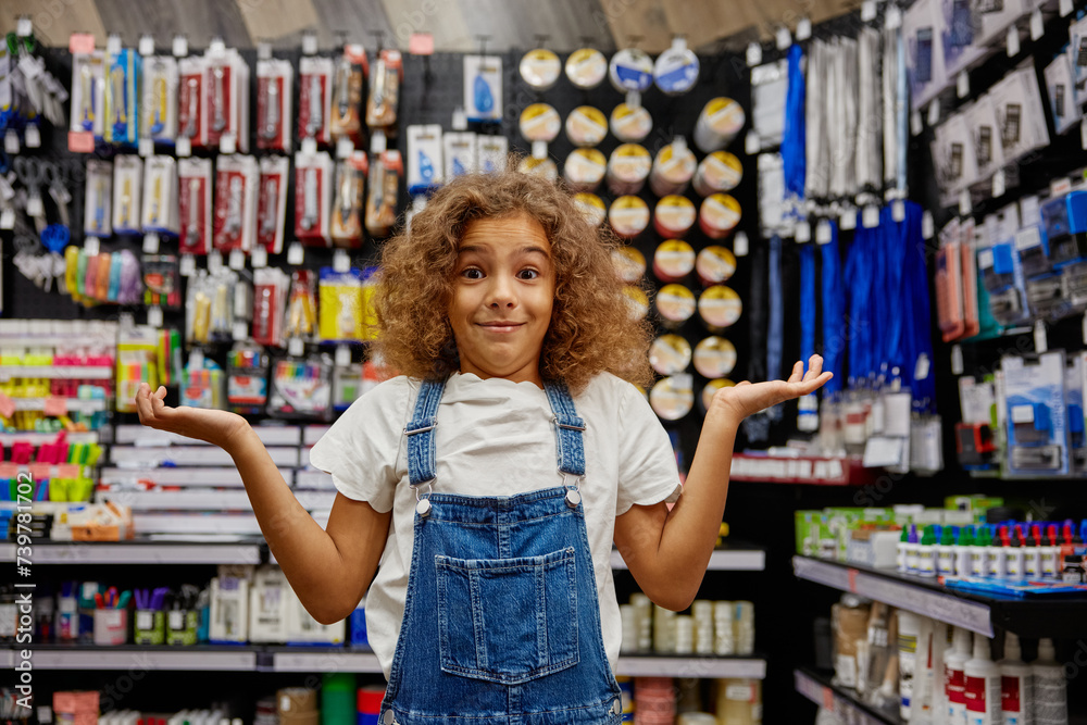 Portrait of funny school girl feeling confused standing at stationery store