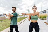 Fitness couple stretching outdoors in the city, showcasing a healthy lifestyle and workout partnership.
