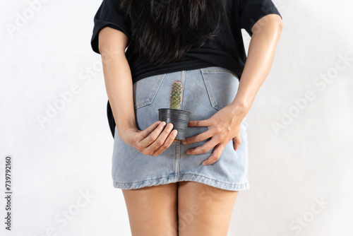 Woman holds cactus near her ass. Hemorrhoids concept.