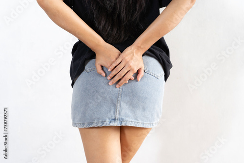 Young woman in jeans holds bottom feeling anal pain. Female suffers from hemorrhoids.