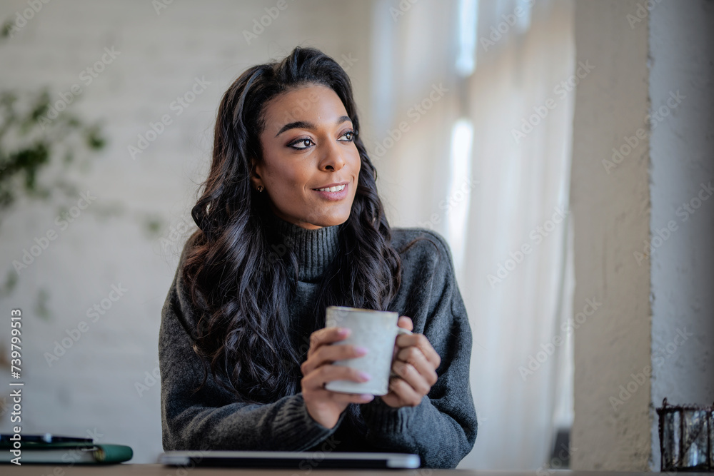 An afro-american woman woman sitting at desk and holding a cup of tea in her hand An afro-american woman woman sitting at desk and holding a cup of tea in her hand