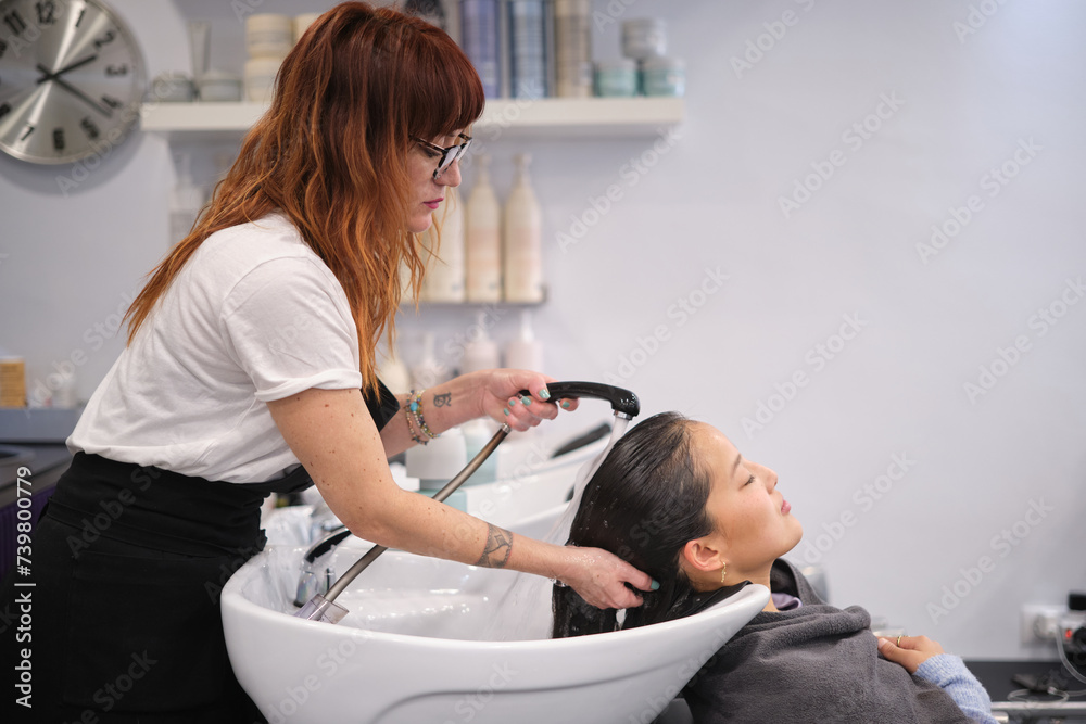 Hairdresser removing the shampoo of the hair of a client Hairdresser removing the shampoo of the hair of a client