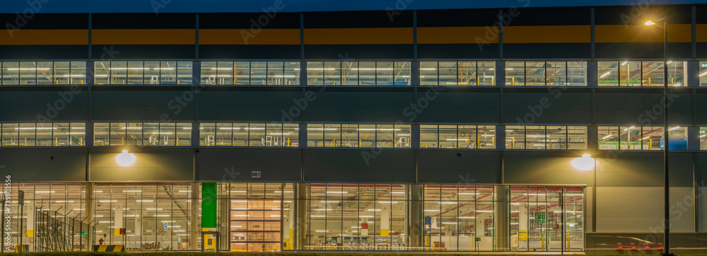 Warehouse facade at night, view of the illuminated warehouse through the windows Warehouse facade at night, view of the illuminated warehouse through the windows