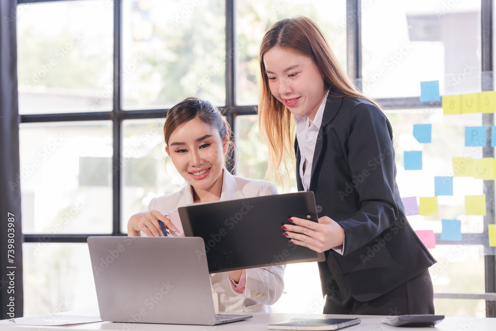 Two young Asian business woman talk, consult, discuss working with new startup project idea presentation analyze plan marketing and investment in the office. Two young Asian business woman talk, consult, discuss working with new startup project idea presentation analyze plan marketing and investment in the office.