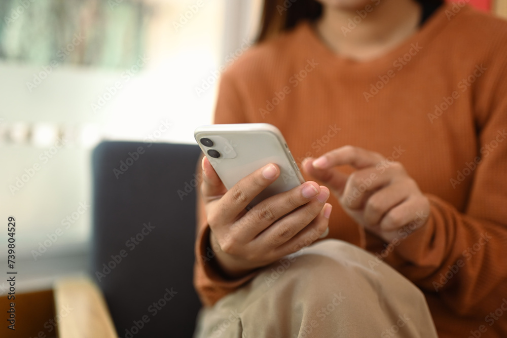 Closeup view young woman texting or chatting on mobile phone while relaxing at home Closeup view young woman texting or chatting on mobile phone while relaxing at home