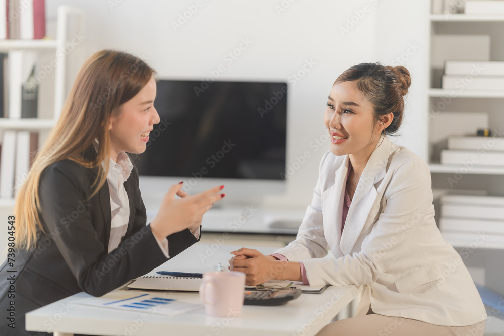 Two young Asian business woman talk, consult, discuss working with new startup project idea presentation analyze plan marketing and investment in the office. Two young Asian business woman talk, consult, discuss working with new startup project idea presentation analyze plan marketing and investment in the office.