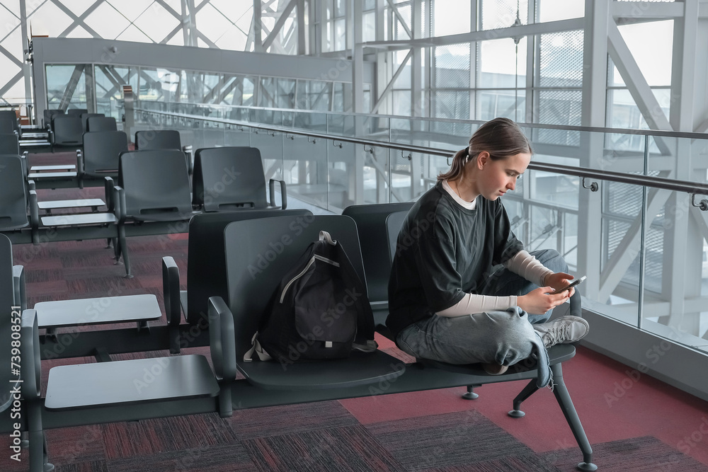 Travel, airport, woman waiting for a flight working on the phone, solo travel, airport transit area, travel experiences, authentic travel