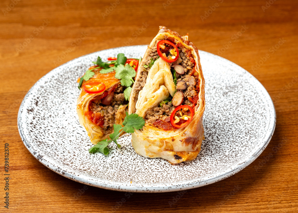 Mexican burrito dish with meat, beans and vegetables on a plate. Mexican burrito dish with meat, beans and vegetables on a plate.