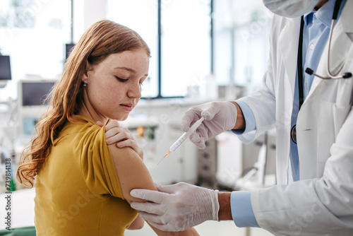 Doctor, pediatrician injecting vaccine into teenage girl arm. Concept of preventive health care and vaccination for teenagers. photo