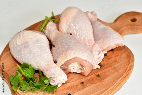Three chicken legs lie on a cutting board, ready to be cooked.