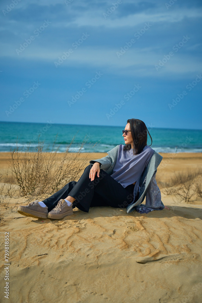 woman in warm clothes walks on the sand dunes