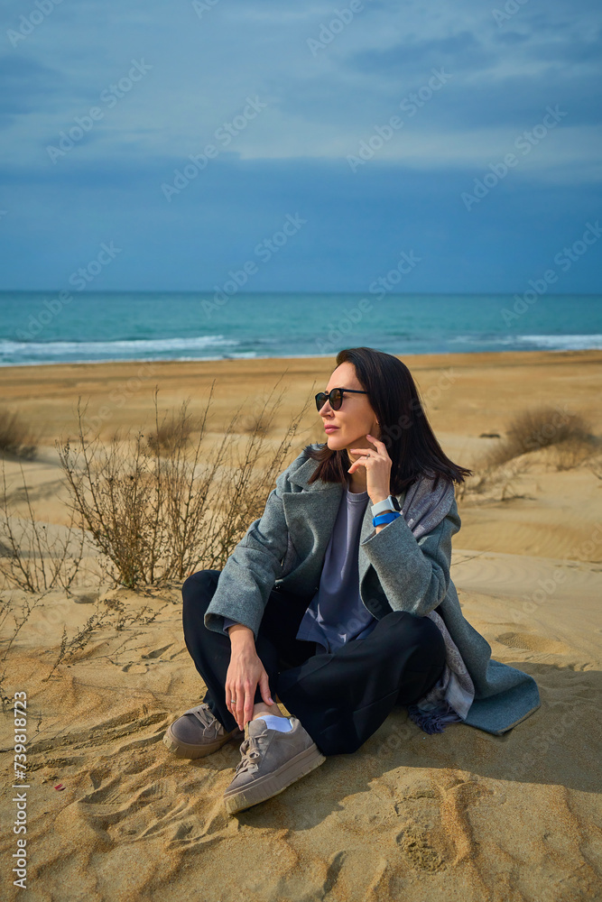 woman in warm clothes walks on the sand dunes