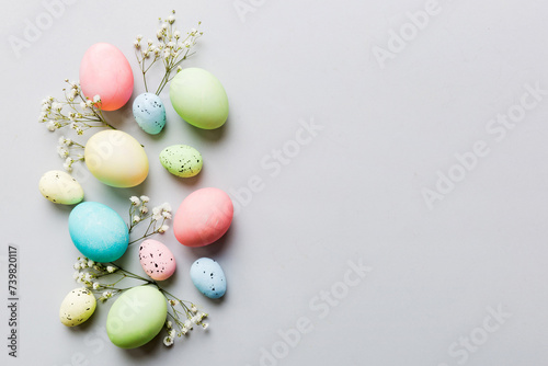 Happy Easter composition. Easter eggs on colored table with gypsophila. Natural dyed colorful eggs background top view with copy space