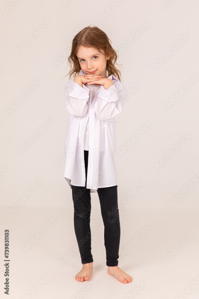 full length portrait of smiling cute little blonde girl in white shirt and black trousers on white background. Copy space. Mock up. full length portrait of smiling cute little blonde girl in white shirt and black trousers on white background. Copy space. Mock up.