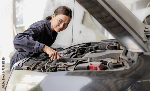 Auto mechanic working in vehicle repair service garage. Long hair woman inspecting breaking automobile engine, motor parts breakdown, examining oil. People in automotive maintenance business concept