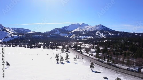 Mammoth Lakes Sierra Mountains California aerial cinematic drone flight winter spring sunny beautiful snow covered town June Lake Crowley Bishop skatepark upward movement photo