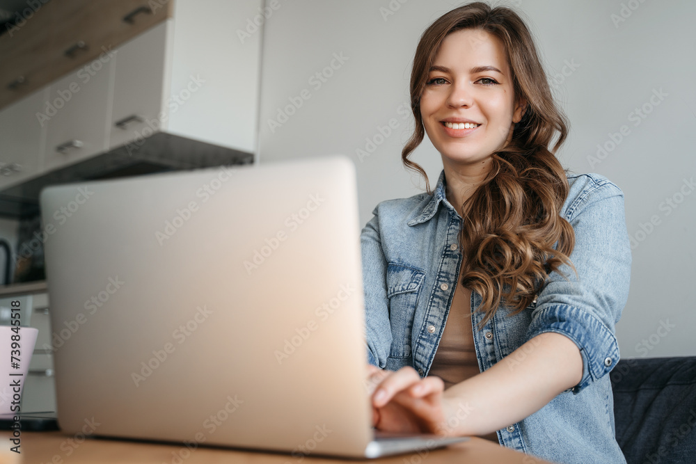 Happy smiling woman sitting on couch, couch and using laptop in living room at home, watching funny video, learning language, video calling, mother working online Happy smiling woman sitting on couch, couch and using laptop in living room at home, watching funny video, learning language, video calling, mother working online