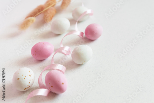 Easter minimalistic concept with easter eggs, ribbon and flowers. Delicate pastel empty background with copy space.
