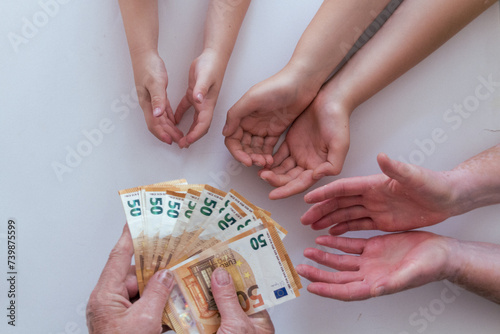 Old grandfather or grandmother hands giving 50 euros banknotes to another pairs of hands of his her wife man and grandchildren photo