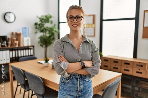 Young caucasian woman business worker smiling confident standing with arms crossed gesture at office photo