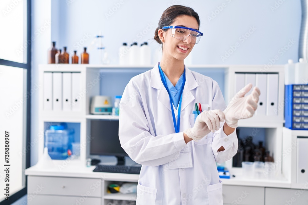Young beautiful hispanic woman scientist smiling confident wearing gloves at laboratory Young beautiful hispanic woman scientist smiling confident wearing gloves at laboratory